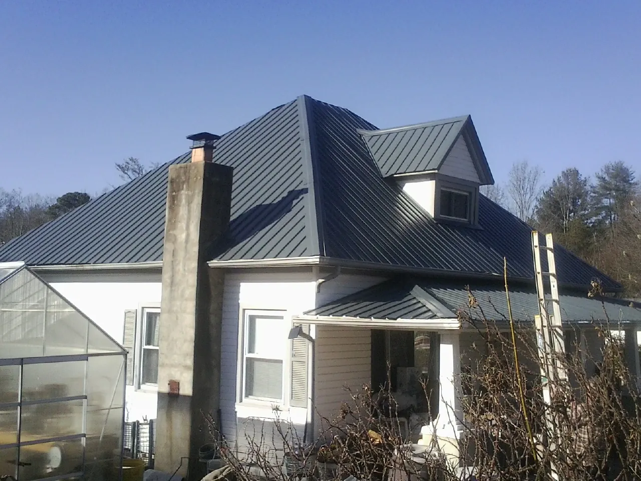 Dark blue standing seam metal roof on a white farmhouse with dormer — Slate & Tile Roof Repair by Roofing Brothers in South Elgin