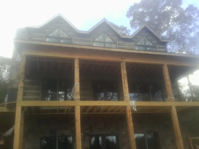 Dormers and porch framing on a large log home under construction — Roof Coating work by our crew in South Elgin