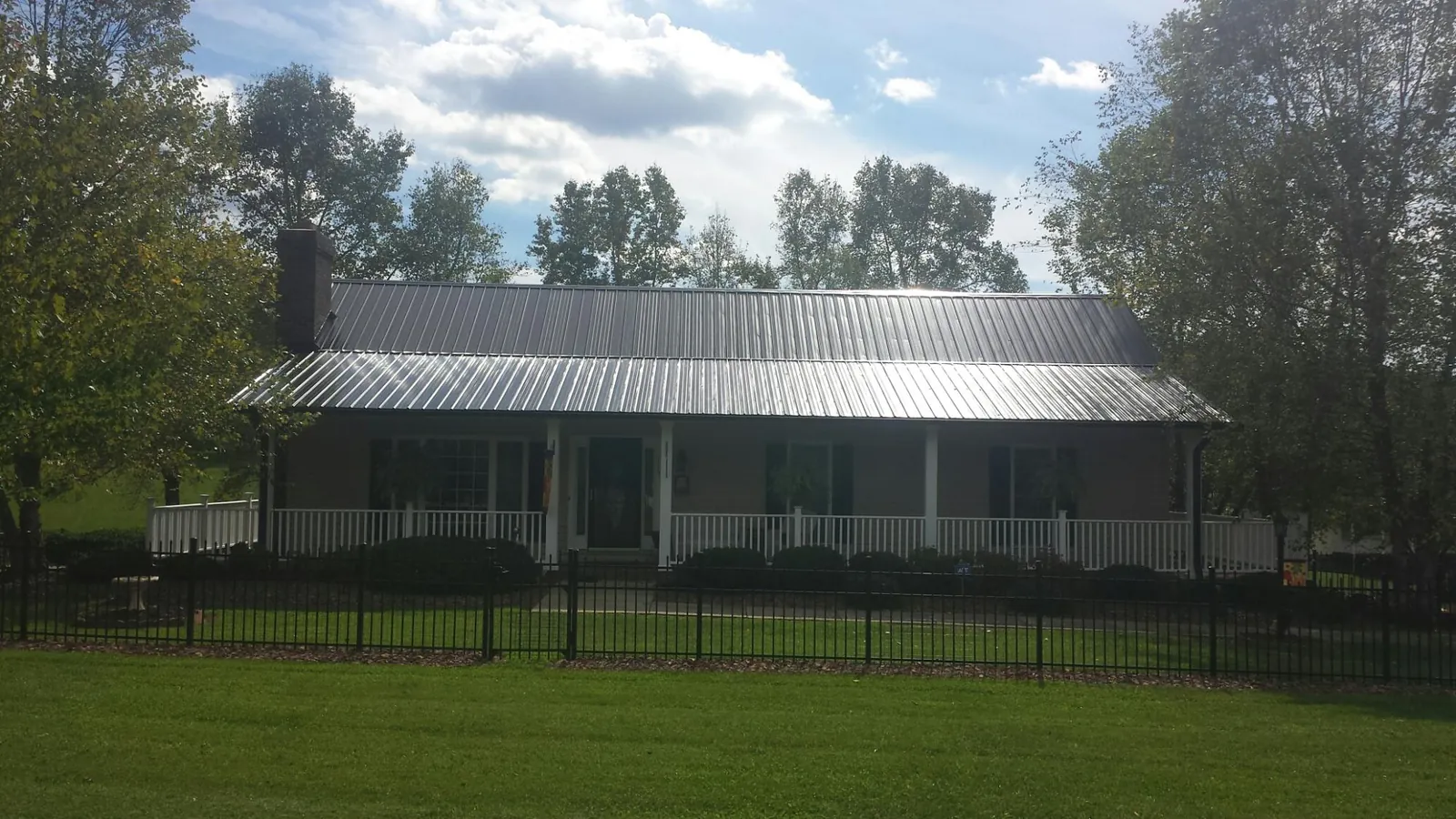 Gray metal roof on a brick ranch with a full width front porch — Gutter Guard Installation work by our crew in South Elgin