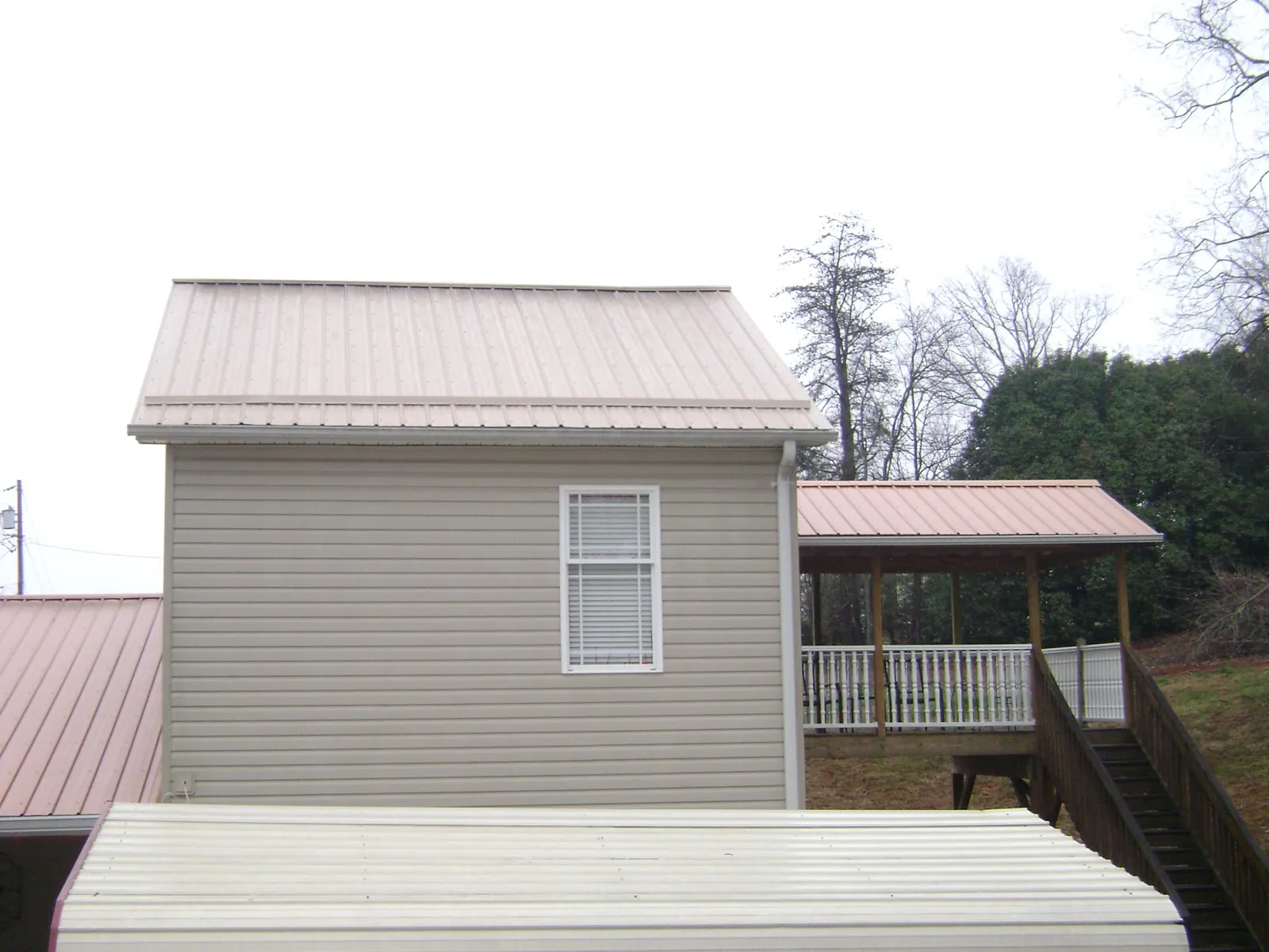 Tan metal roofs on a two story addition and attached porch, from a Roof Replacement job in South Elgin