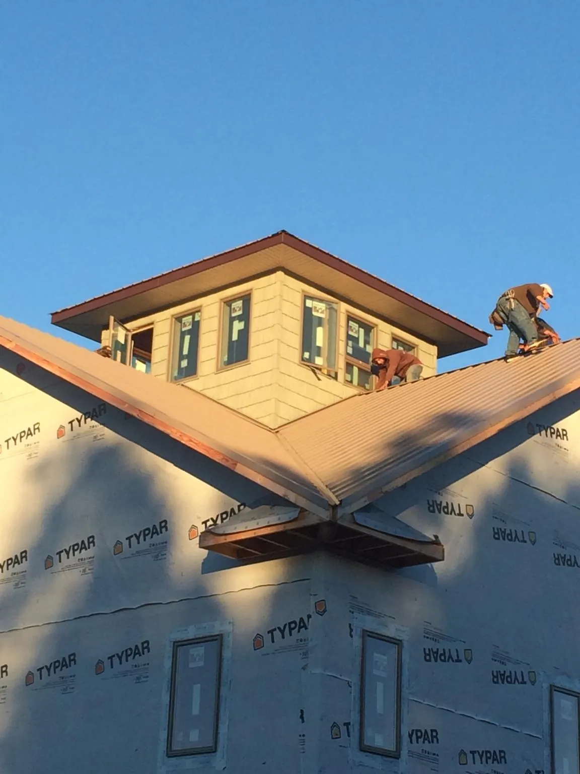 Roofers working around a rooftop cupola on a new metal roof at sunset — Roof Waterproofing in South Elgin by Roofing Brothers